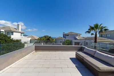 a couch sitting on a patio in front of some houses at Ocean Whisper Terrace Villa in Cape Town