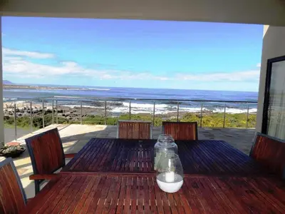 a wooden table with a view of the ocean at Whalesong Villa in Hermanus