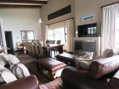 a living room with couches and a table with a fireplace at Whalesong Villa in Hermanus