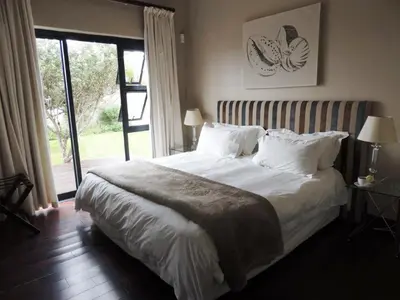 a bedroom with a large white bed with a window at Whalesong Villa in Hermanus