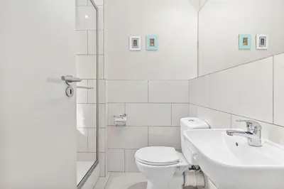 a white bathroom with a toilet and a sink at Manhattan Wharfside 301 in Cape Town