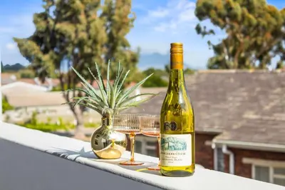 a bottle of wine and two glasses on a balcony at The Orion 18 in Table View