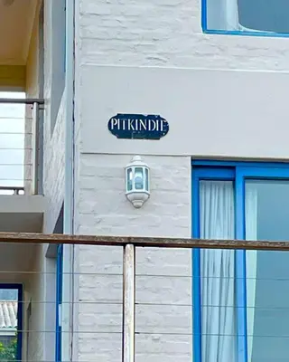 a sign on the side of a building with a window at Pitkindie Oceanfront Escape in Hermanus