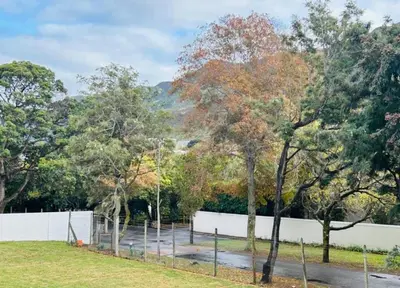a park with trees and a white fence at Heaven & Earth Apartment 8 in Hermanus