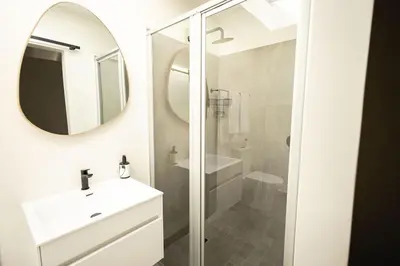 a white bathroom with a sink and a mirror at Heaven & Earth Apartment 8 in Hermanus
