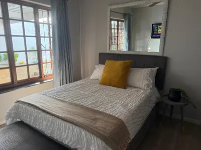 a bedroom with a bed with a yellow pillow and a mirror at Mopanie House in Brackenfell