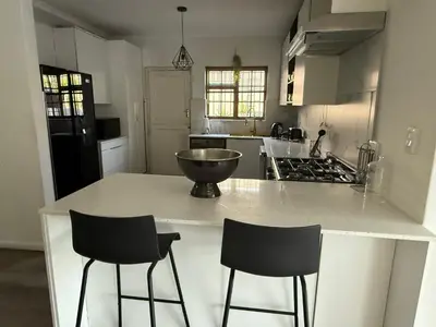 a kitchen with a counter with two bar stools at Mopanie House in Brackenfell
