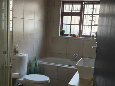 a bathroom with a toilet and a tub and a sink at Mopanie House in Brackenfell