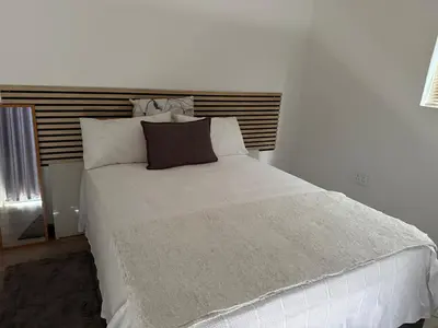 a bedroom with a white bed with a brown pillow at Mopanie House in Brackenfell