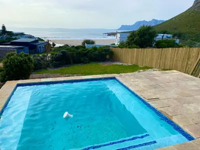 a swimming pool with a view of the beach at Sea and Sky Rooiels in Rooiels
