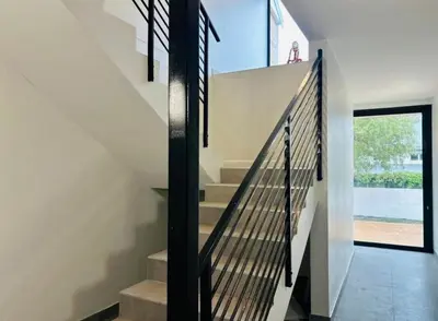 a staircase with black railings in a house at Valley's Embrace Apartment 7 in Hermanus