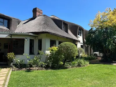 an old house with a thatched roof and a yard at Shire Lodge in Cape Town