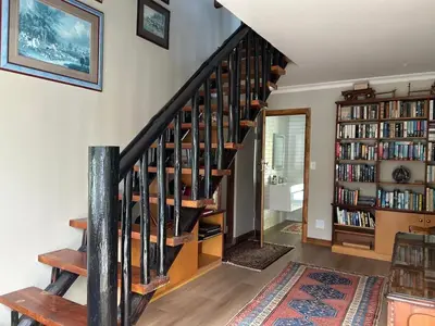 a staircase in a living room with a book shelf at Shire Lodge in Cape Town