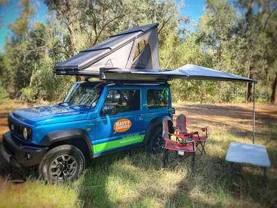 a blue jeep with a tent and a chair at Happy Campers South Africa in Strand