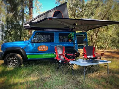 a blue jeep with a tent and two chairs at Happy Campers South Africa in Strand