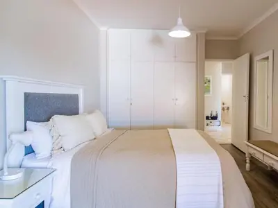 a white bedroom with a large bed with white pillows at Whales & Wonders Guesthouse in Hermanus