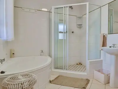 a white bathroom with a tub and a sink at Whales & Wonders Guesthouse in Hermanus