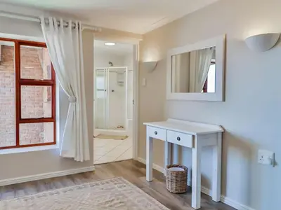 a white bathroom with a sink and a mirror at Whales & Wonders Guesthouse in Hermanus