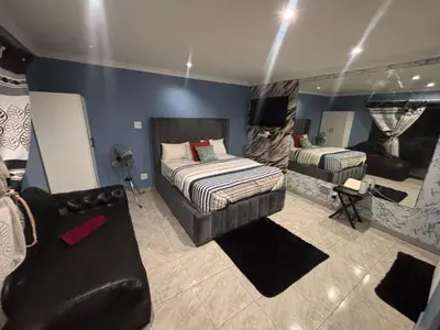 a bedroom with two beds and a couch in it at Browns villa and construction pty ltd in Cape Town