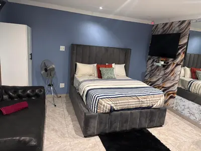 a bedroom with a large bed and a chair at Browns villa and construction pty ltd in Cape Town