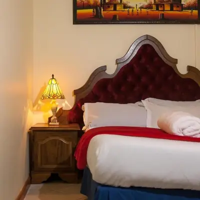 a bedroom with a bed with a red headboard and a lamp at Harmony Lodge in Elsiesrivier