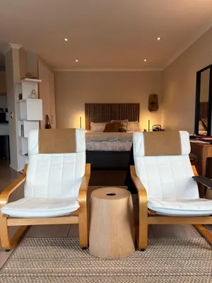 a bedroom with two white chairs and a bed at Treetops Studio in Cape Town