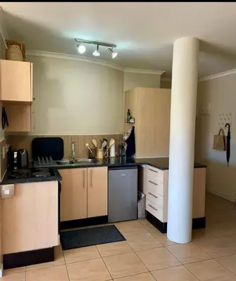 a kitchen with brown cabinets and a pole in it at Treetops Studio in Cape Town