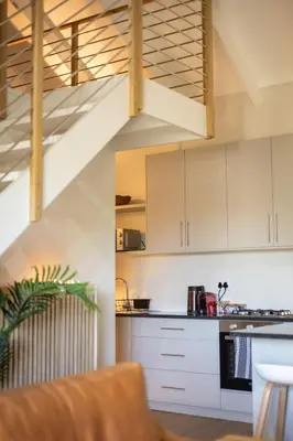 a kitchen with white cabinets and a staircase at Aurora Valley Escape Apartment 9 in Hermanus