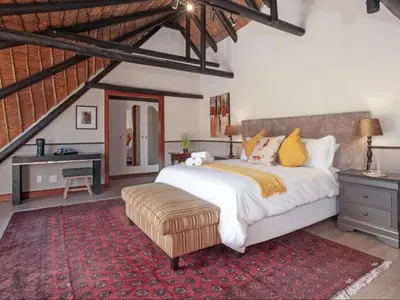 a bedroom with a large bed and a desk at Leopard Lodge in Hermanus