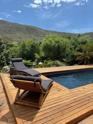 a chair sitting on a deck next to a swimming pool at Leopard Lodge in Hermanus