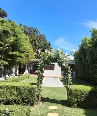 a garden with an arch in front of a house at La Mode Garden Cottage in Paarl