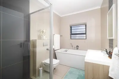 a white bathroom with a toilet and a sink at Peppertree Villa in Brackenfell