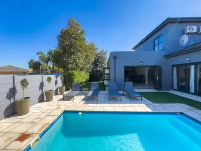 a swimming pool in front of a house at Peppertree Villa in Brackenfell