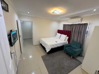 a small room with a bed and a blue chair at Joy House in Cape Town