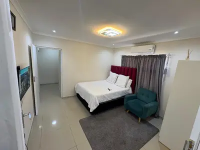 a small bedroom with a bed and a blue chair at Joy House in Cape Town