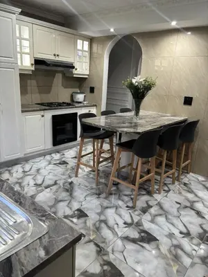 a kitchen with a table and chairs on a marble floor at Luxurious Family Home 2