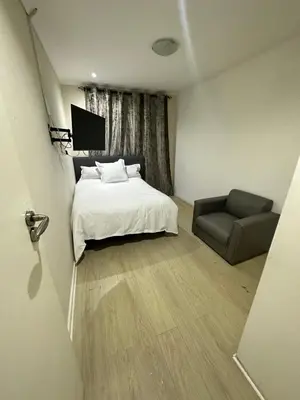 a bedroom with a bed and a chair and a television at Joy House in Cape Town
