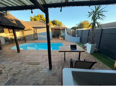 a patio with a table and a swimming pool at Joy House in Cape Town