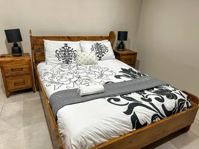 a bed with black and white sheets and pillows at Blade Flatlet 2 in Silver Sands