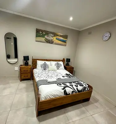 a bedroom with a bed and a tv on a wall at Blade Flatlet 2 in Silver Sands