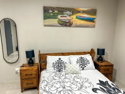 a bedroom with a bed with two lamps and a painting at Blade Flatlet 2 in Silver Sands