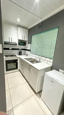 a kitchen with white cabinets and a sink and a window at Blade Flatlet 2 in Silver Sands