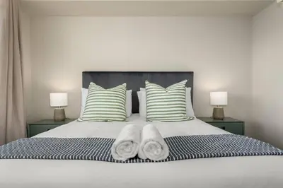 a bedroom with a bed with two pillows and two lamps at Modern 2 Bed Century City Apartment, Pool and Braai in Cape Town