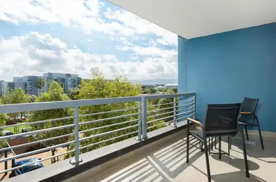 a balcony with two chairs and a view of a city at Modern 2 Bed Century City Apartment, Pool and Braai in Cape Town