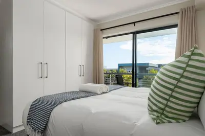 a bedroom with a bed with a large window at Modern 2 Bed Century City Apartment, Pool and Braai in Cape Town
