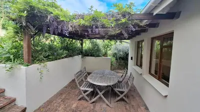a patio with a table and chairs on the side of a house at The Cottage, Heide Avenue in Somerset West