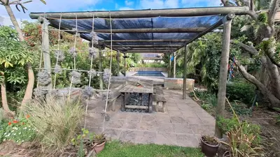 a patio with a table and a canopy in a garden at The Cottage, Heide Avenue in Somerset West