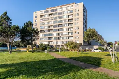 a tall building with a park in front of it at Modern 1 Bedroom Table Mountain View Hideaway, Milnerton in Cape Town