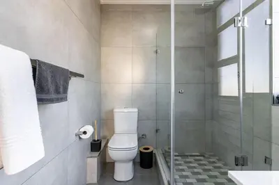 a bathroom with a toilet and a glass shower at Modern 1 Bedroom Table Mountain View Hideaway, Milnerton in Cape Town