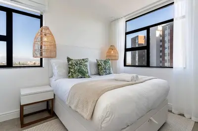 a bedroom with white walls and large windows at Modern 1 Bedroom Table Mountain View Hideaway, Milnerton in Cape Town